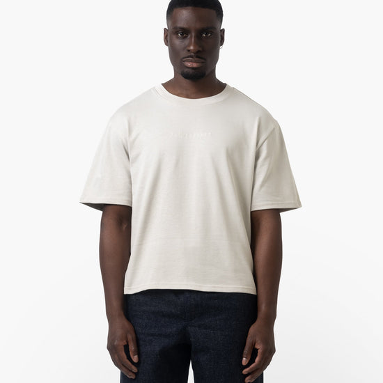 A man wearing a white tshirt on a white background facing forward 