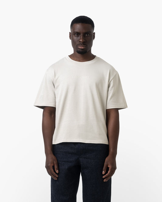 A man wearing a white tshirt on a white background facing forward 