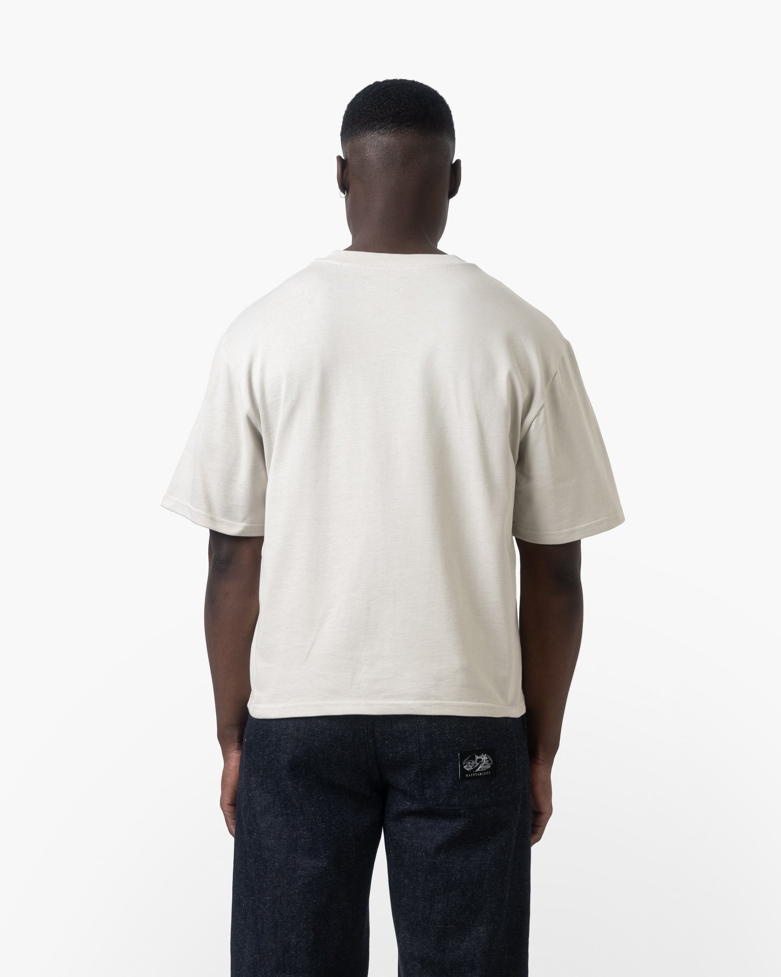 A man facing backwards wearing a white tshirt on a white background 
