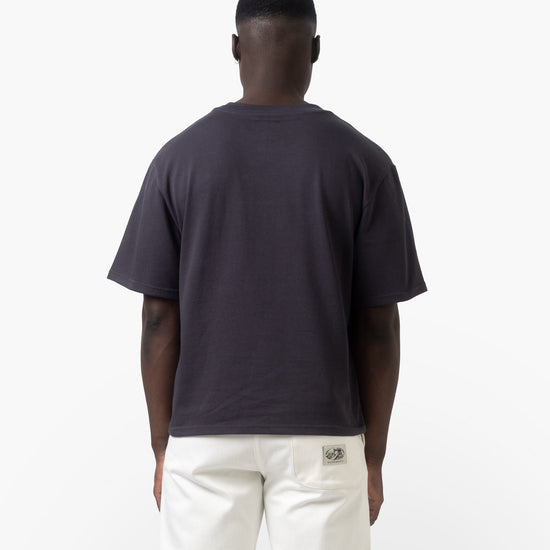 A man wearing a charcoal shirt on a white background facing back 