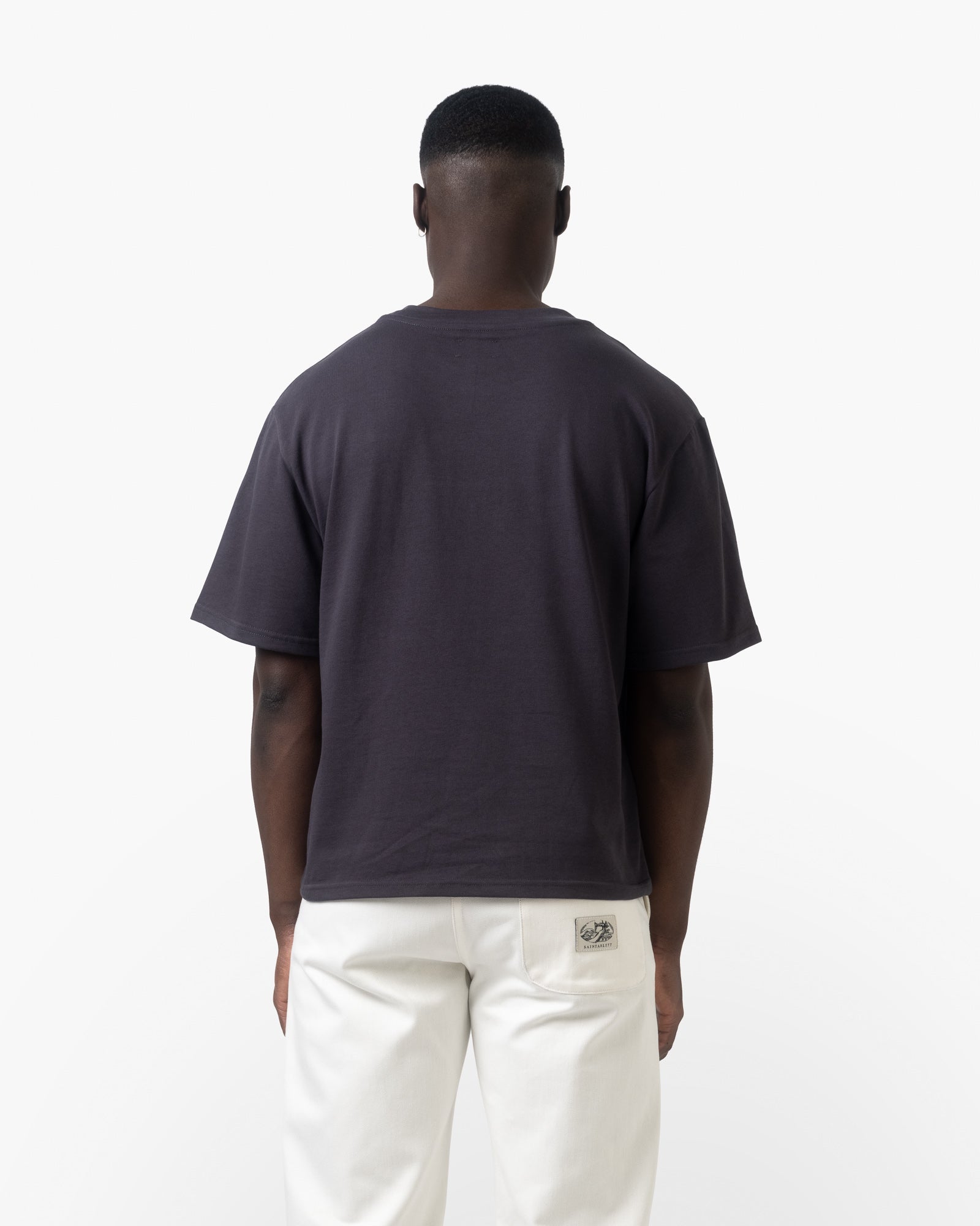 A man wearing a charcoal shirt on a white background facing back 