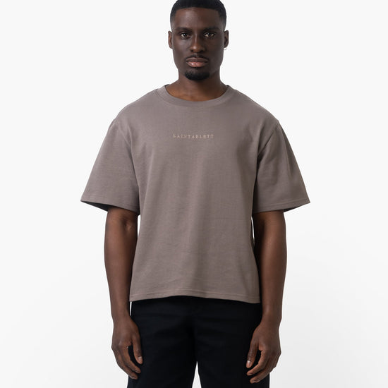 Man wearing a brown t-shirt with text on a white background