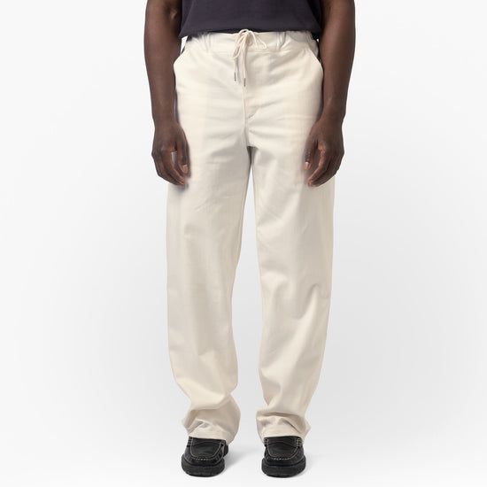 Person wearing a navy shirt and beige pants on a white background