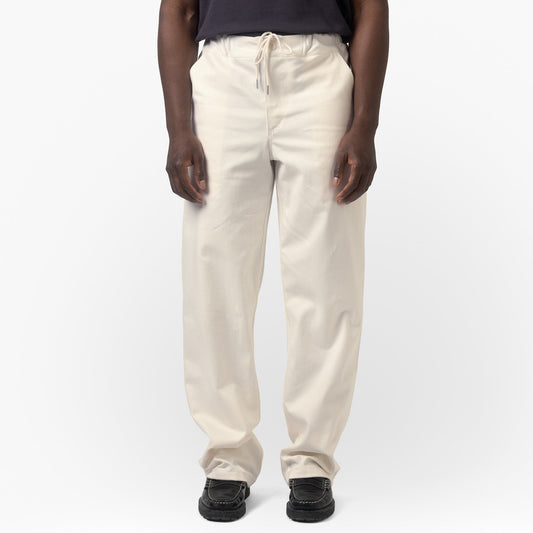 Person wearing a navy shirt and beige pants on a white background