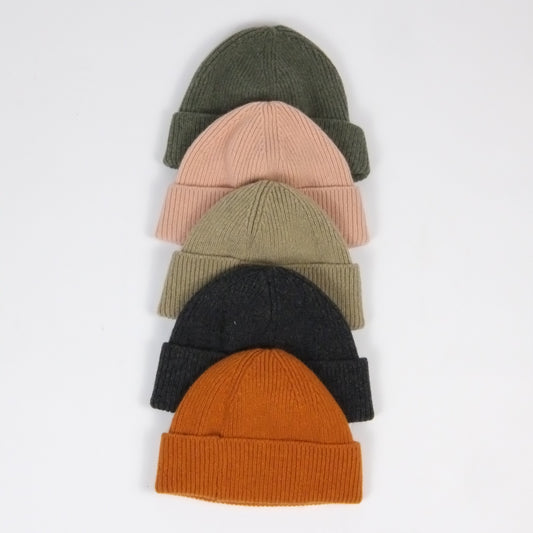 Five knit beanies in different colors arranged on a light gray background
