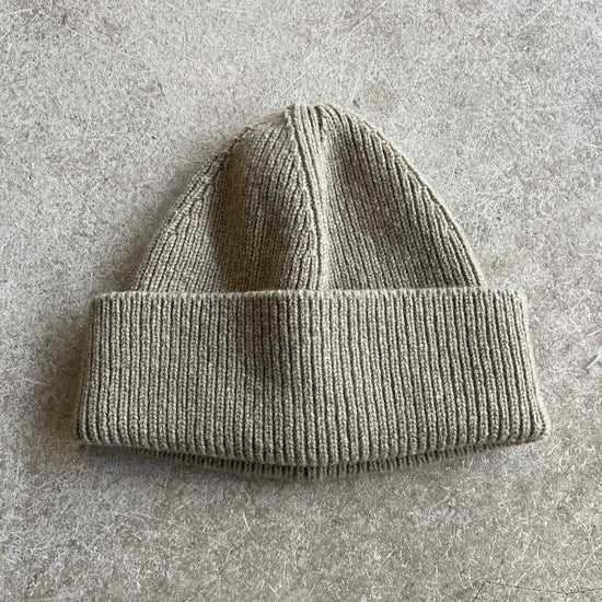 Gray knit beanie on a textured grey surface