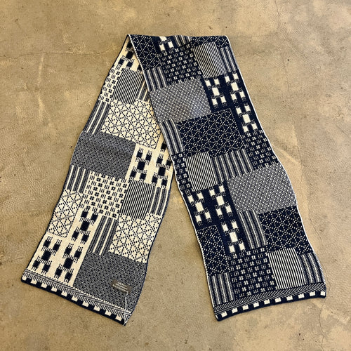 Patchwork blue and white knitted scarf on a concrete background 