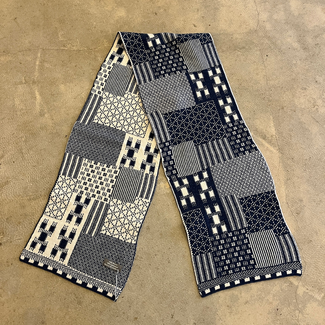 Patchwork blue and white knitted scarf on a concrete background 