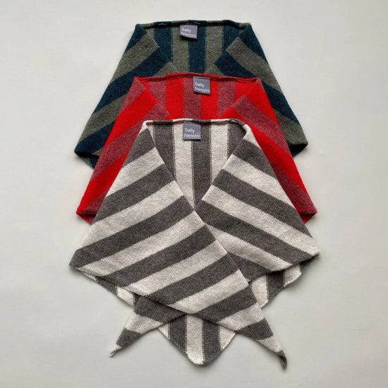 Three folded scarves in red, green, and gray stripes on a light gray background
