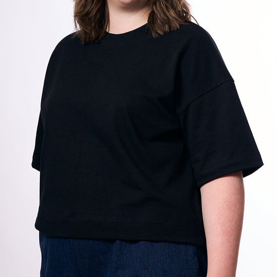 Person wearing a black oversized t-shirt against a white background