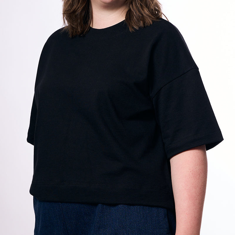 Person wearing a black oversized t-shirt against a white background