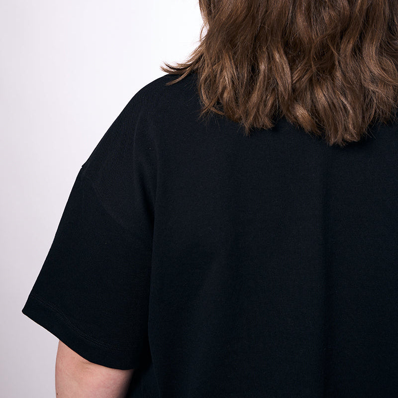 Person wearing a black shirt with long brown hair on a white background