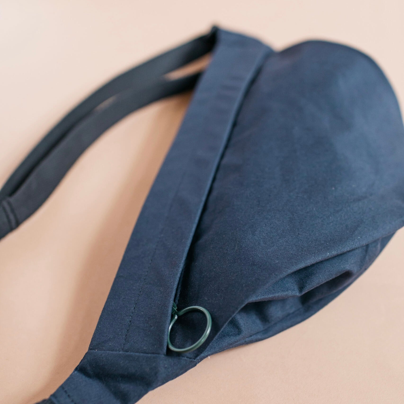 Navy blue bag worn over one shoulder on a beige background