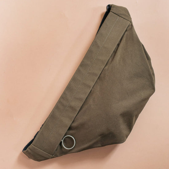 Olive green waist bag on a beige background