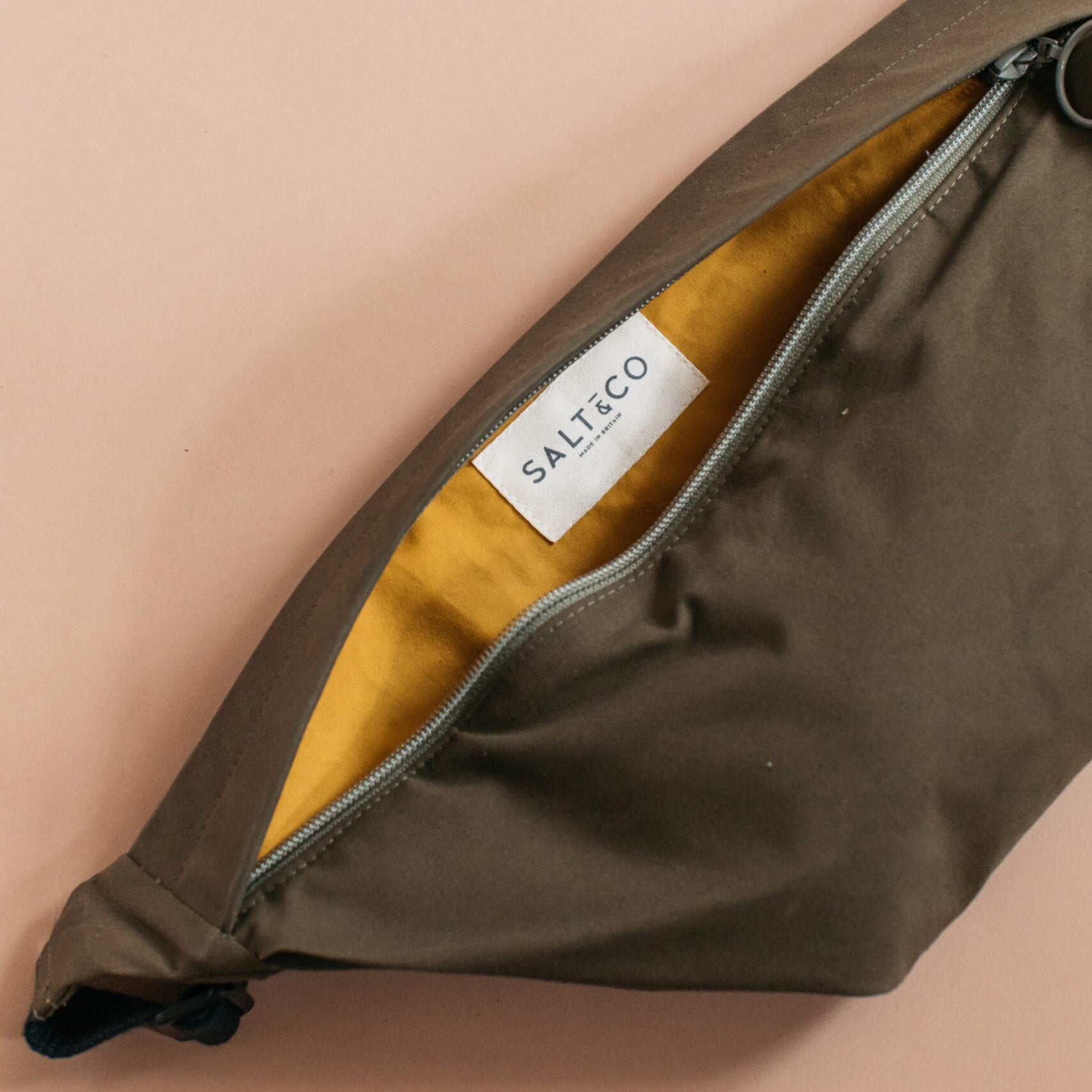 Brown pouch with a visible brand label on a beige background