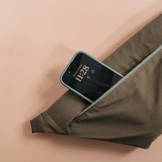 A bag with a phone in it on a beige backgground 