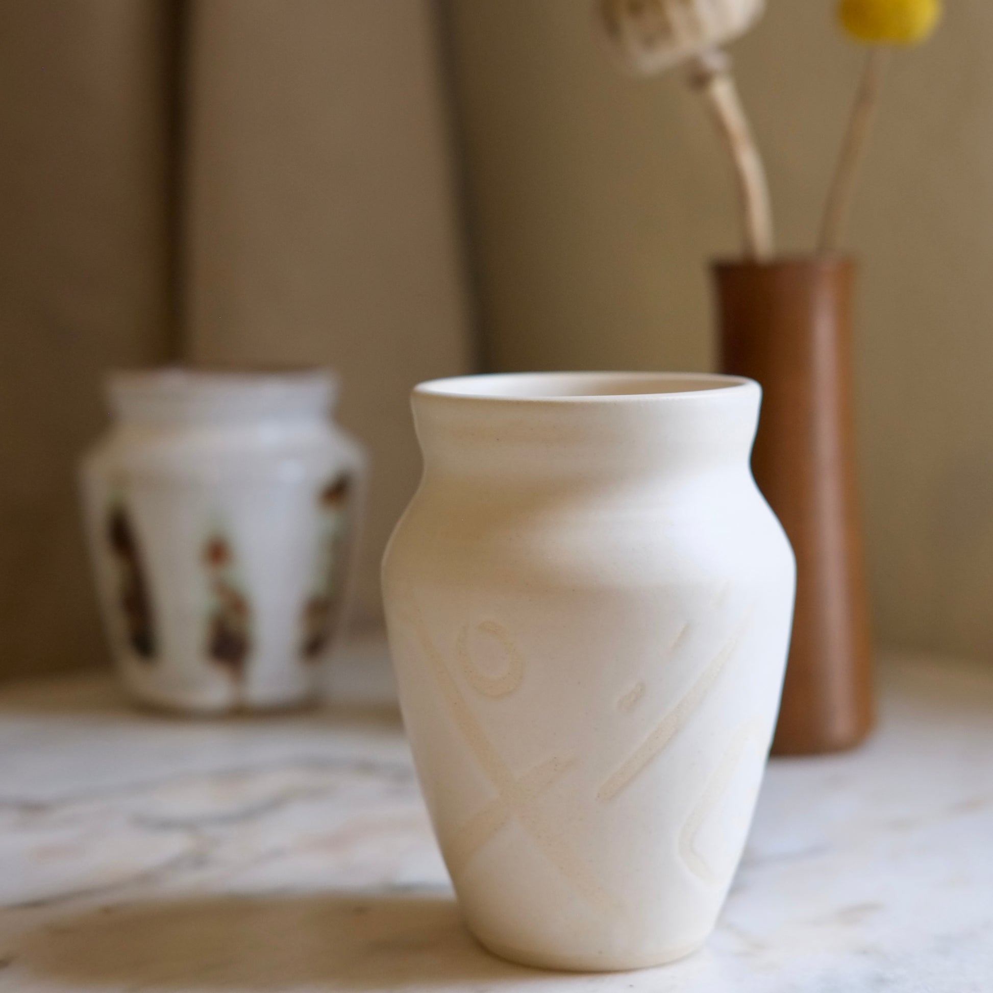 White ceramic vase on a marble surface with blurred background