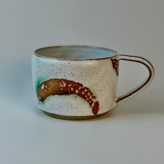 Speckled ceramic mug with a handle on a plain background