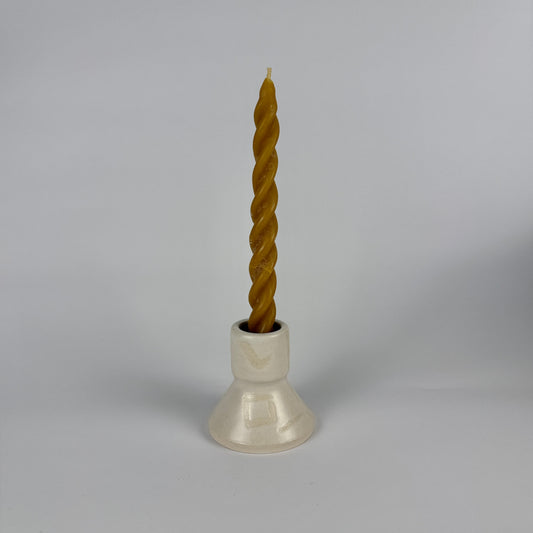 Twisted candle in a white holder on a gray background