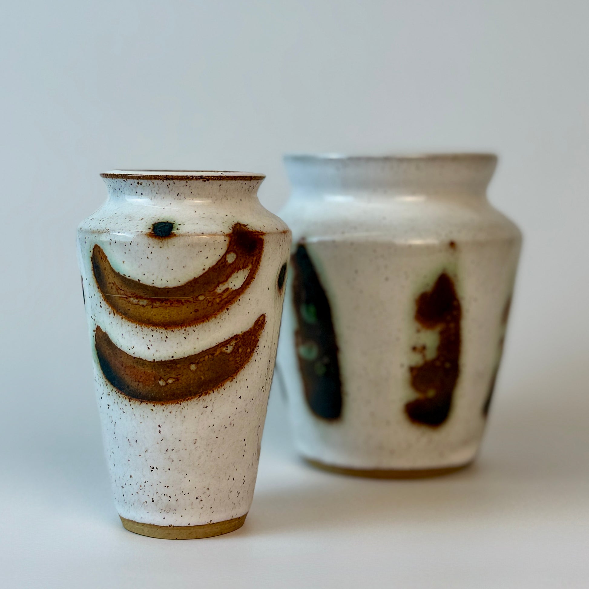 Two ceramic vases with brown abstract designs on a white background