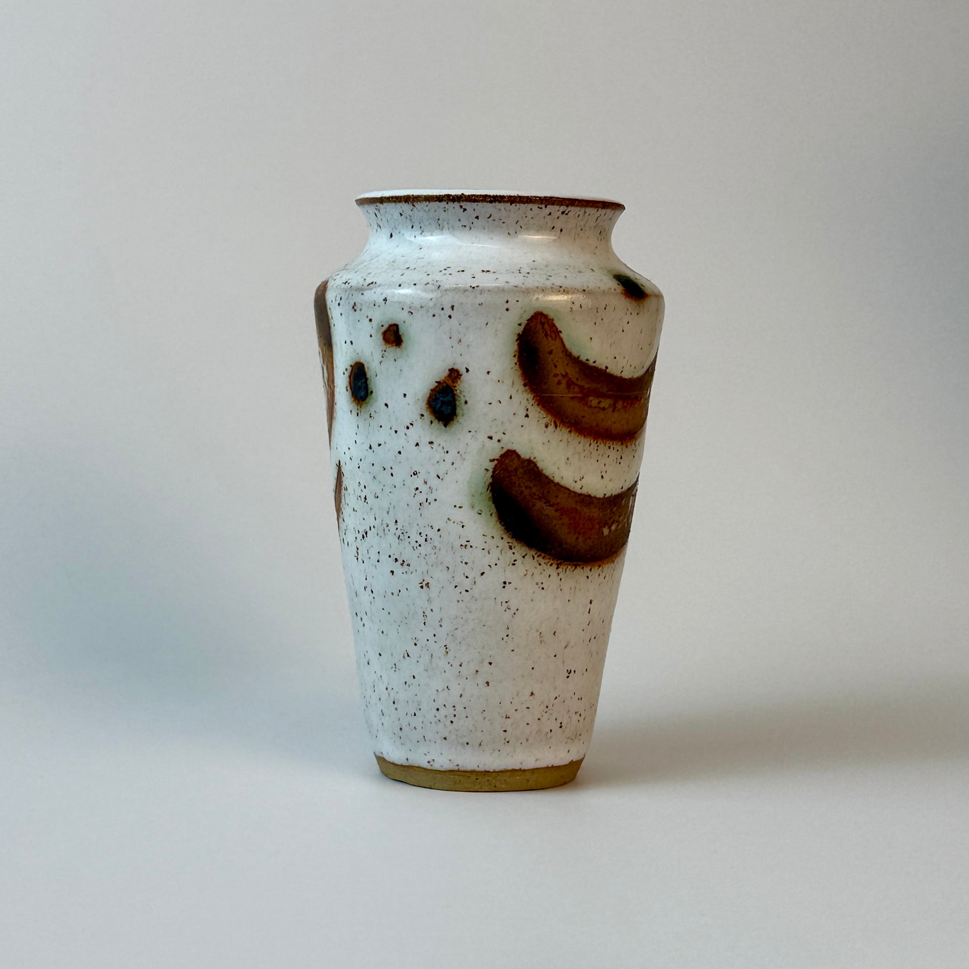 Ceramic vase with brown and black speckled design on a plain background