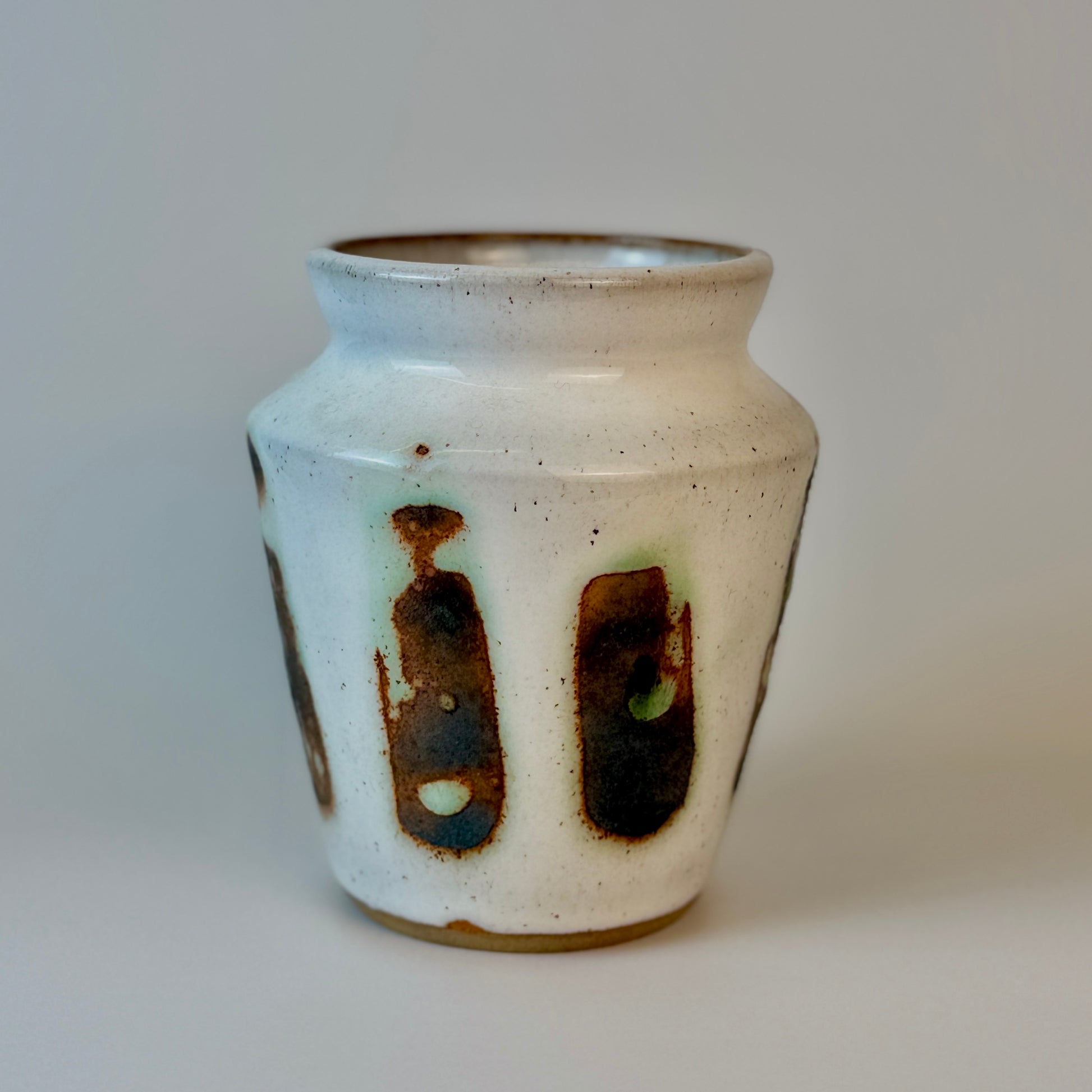 Ceramic vase with speckled glaze and brown accents on a plain background