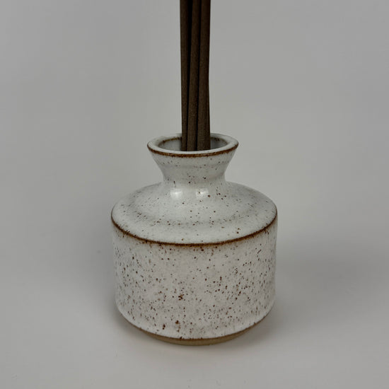 Speckled ceramic bottle with a dark brown base on a gray background