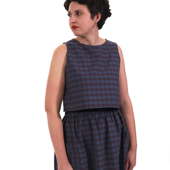 model wears plum and navy check cotton top and skirt on a white background