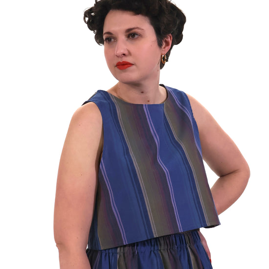 Woman wearing a blue and lilac striped top and trousers on a white background