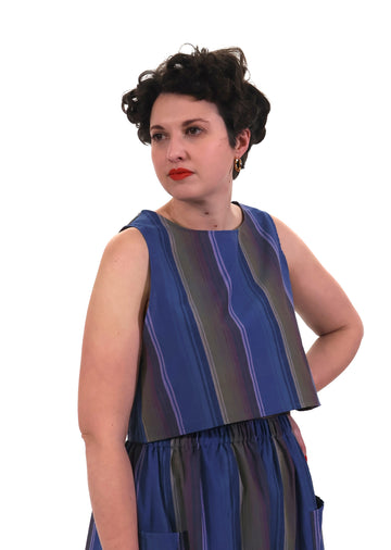 Woman wearing a blue and lilac striped top and trousers on a white background