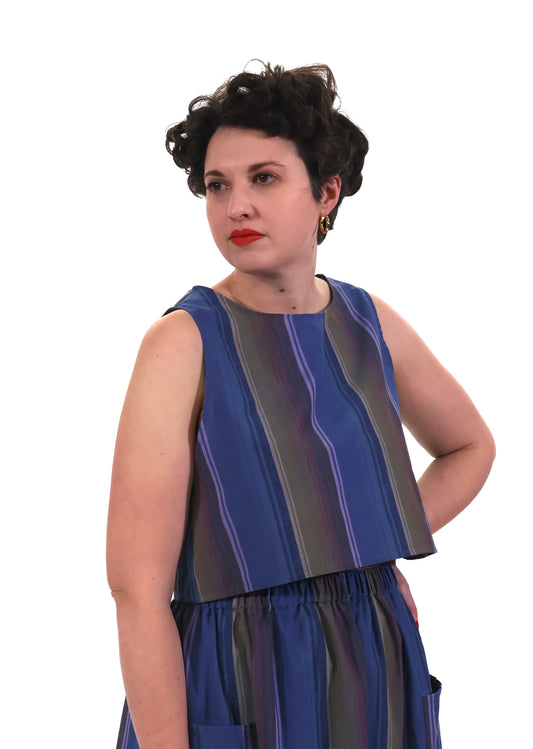 Woman wearing a blue and lilac striped top and trousers on a white background
