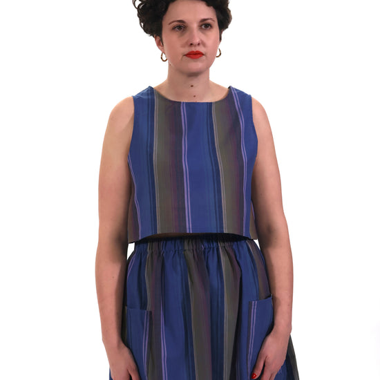 Model wearing blue and lilac stripe cropped tank top with matching gathered skirt in front of a white background