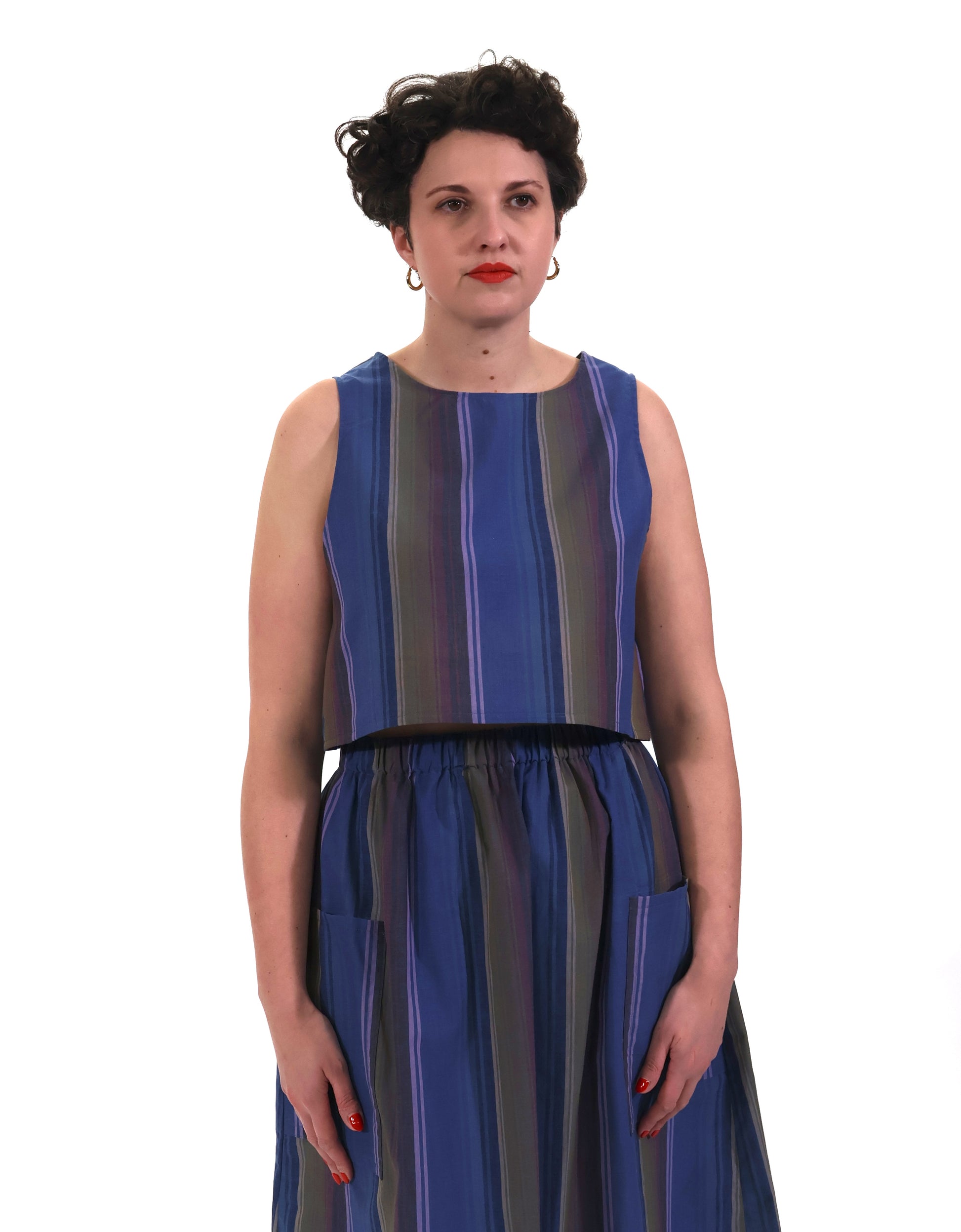 Model wearing blue and lilac stripe cropped tank top with matching gathered skirt in front of a white background