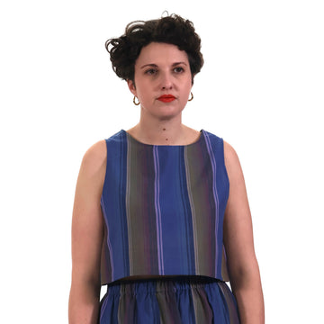 Model wearing blue and lilac stripe cropped tank top with matching gathered skirt in front of a white background