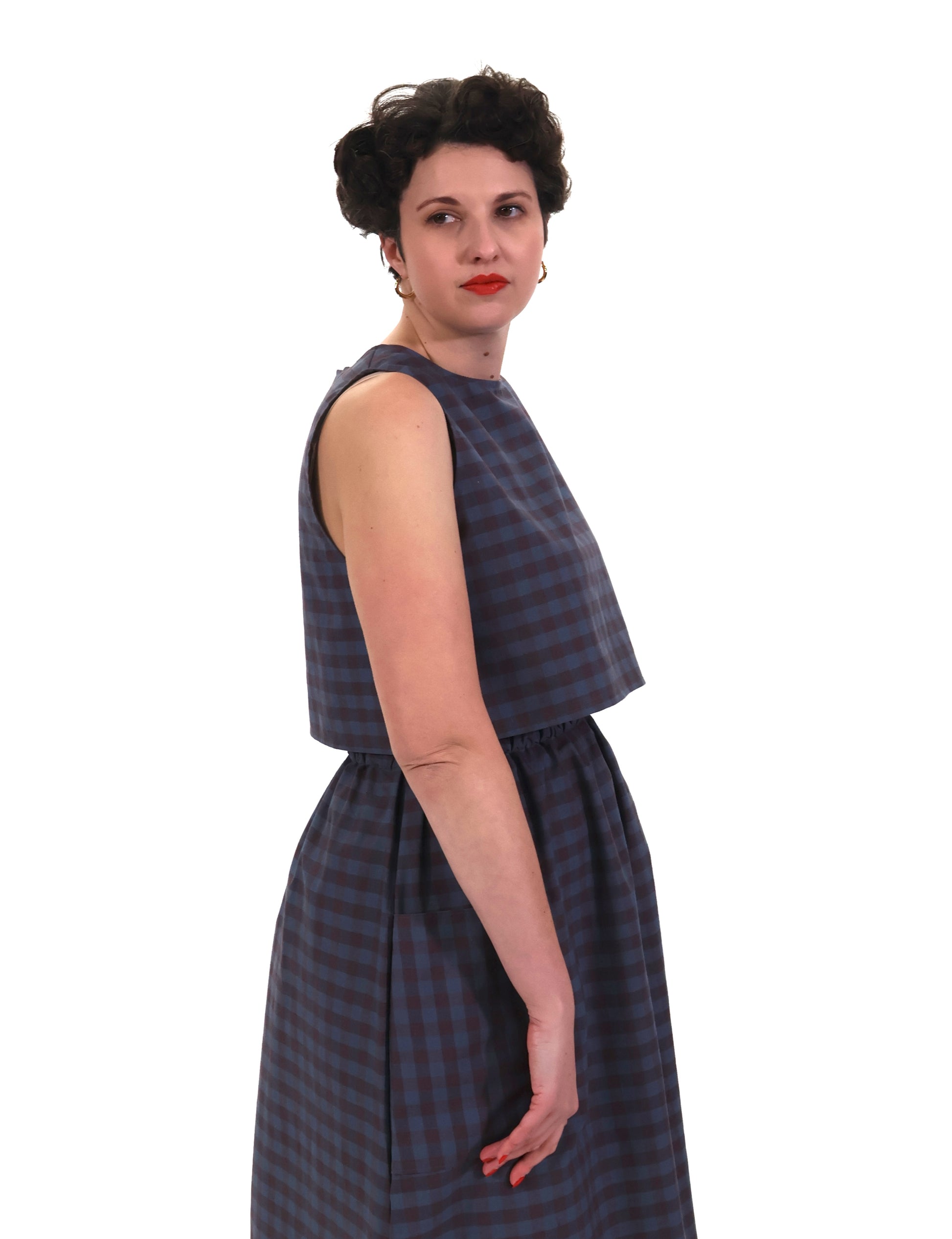 Woman wearing a sleeveless blue and purple check top and skirt on a white background