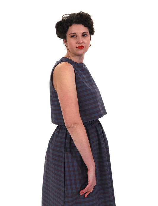 Woman wearing a sleeveless blue and purple check top and skirt on a white background