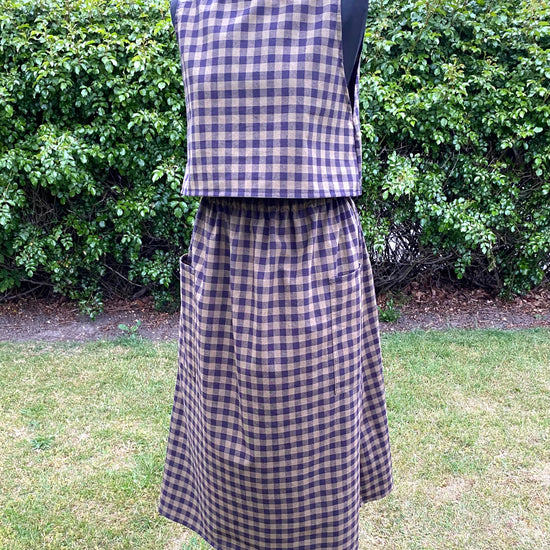 Black and green check top and skirt on a mannequin against a green outdoor background