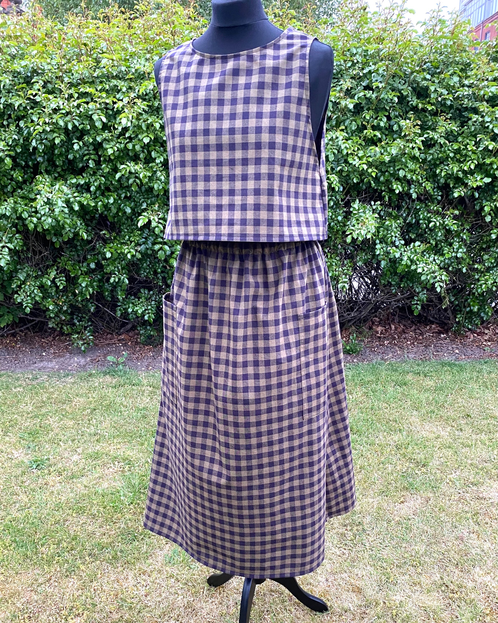 Black and green check top and skirt on a mannequin against a green outdoor background