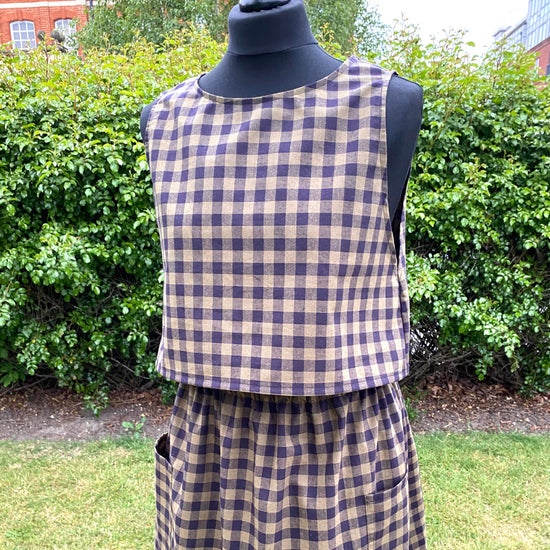 Black and khaki top and skirt on a mannequin against a green outdoor background