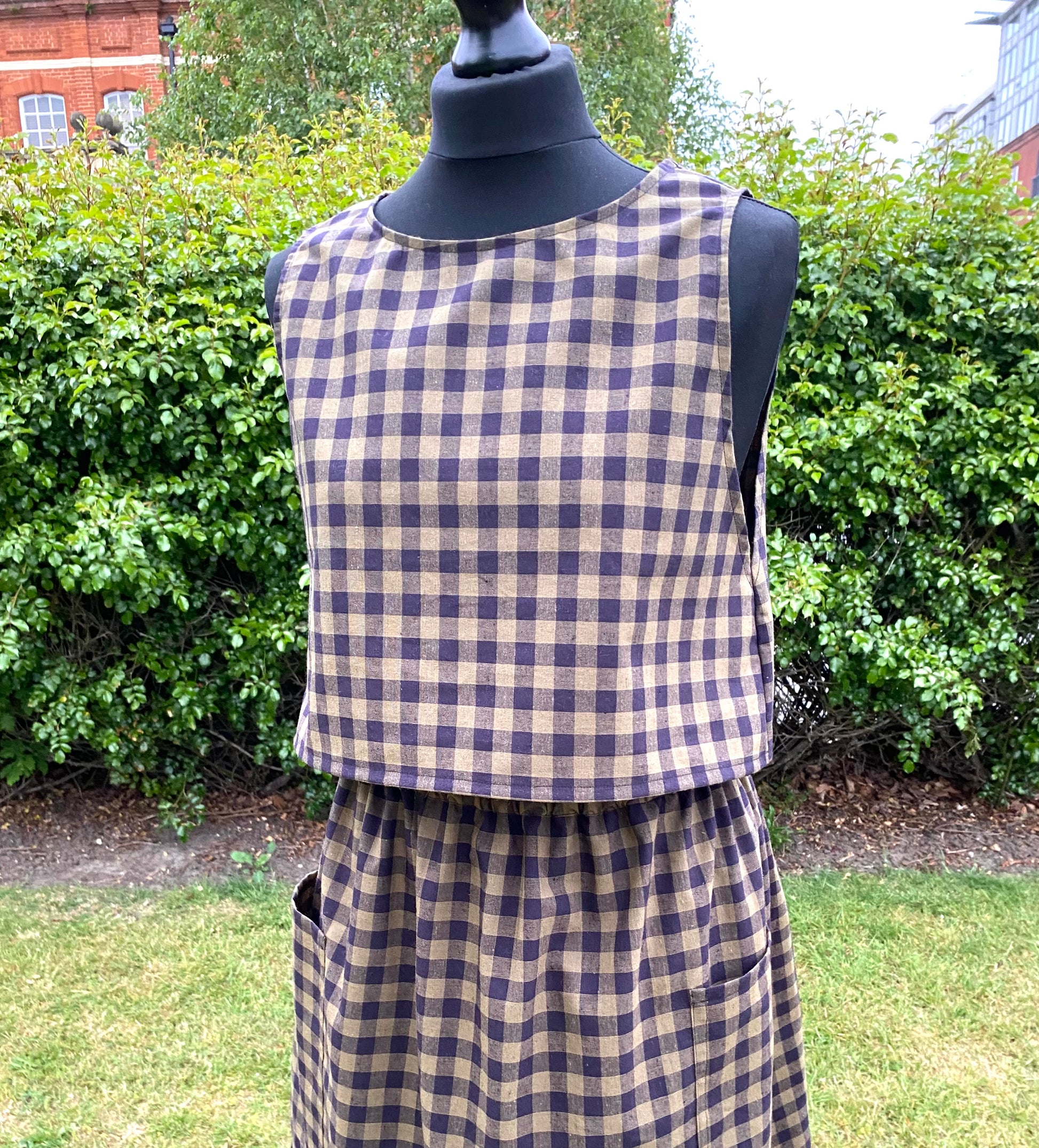 Black and khaki top and skirt on a mannequin against a green outdoor background