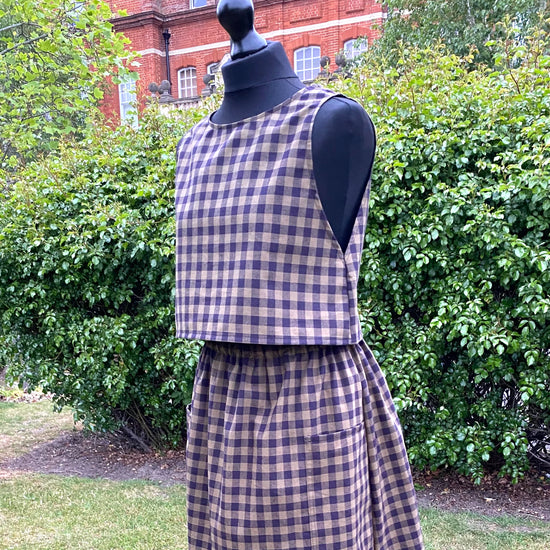 Mannequin wearing a black and khaki top and skirt set with greenery in the background