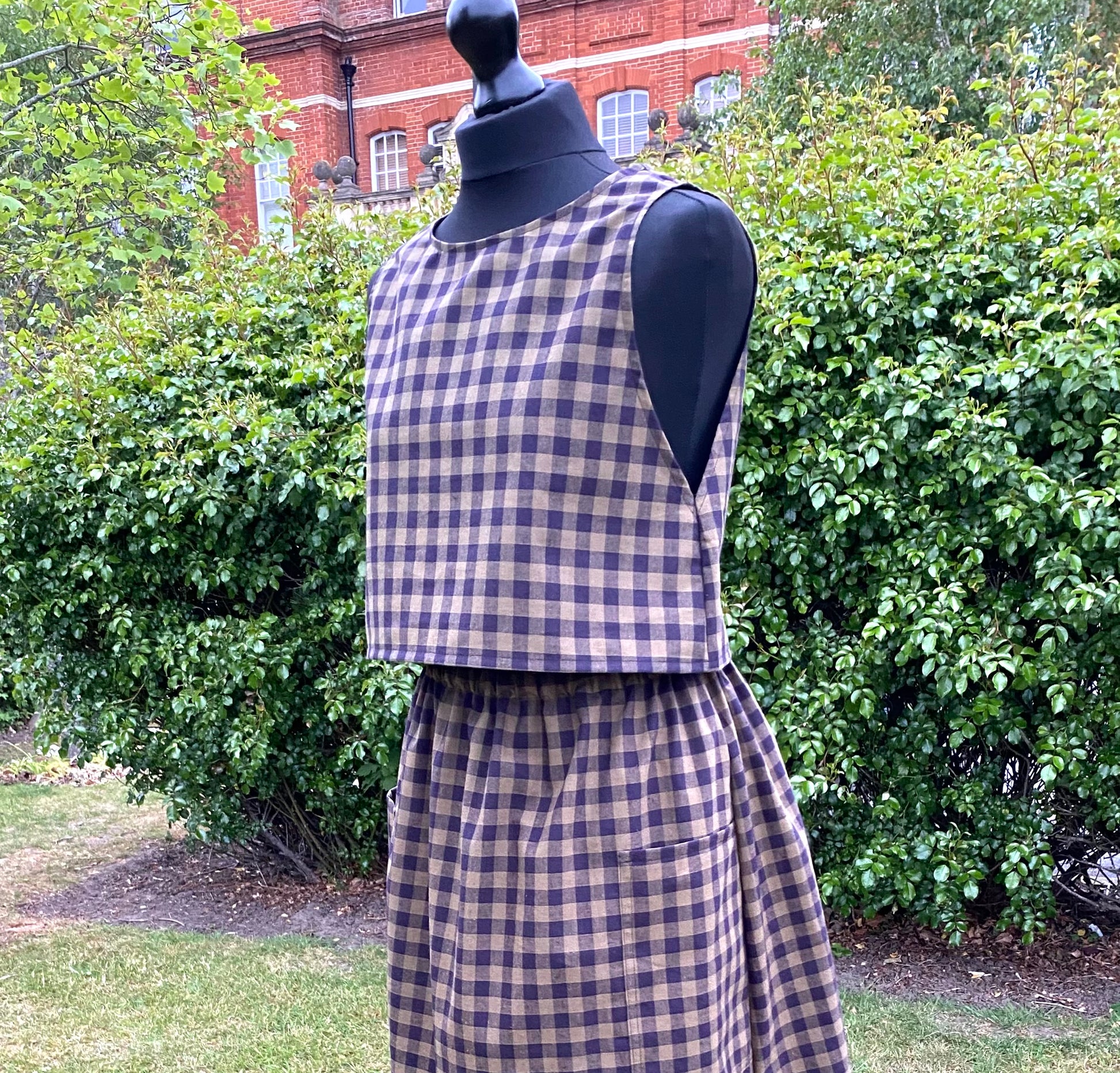 Mannequin wearing a black and khaki top and skirt set with greenery in the background