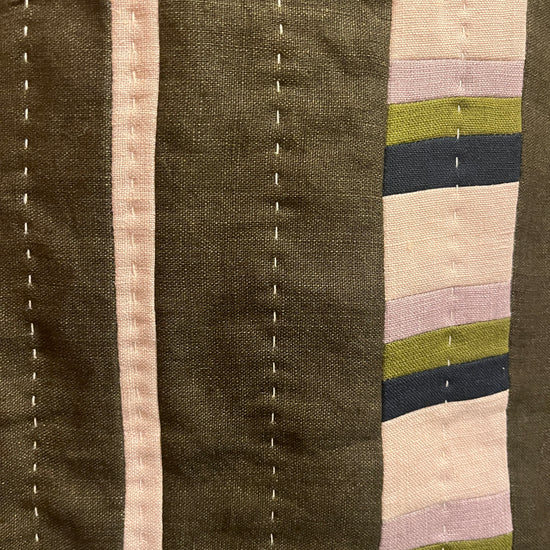 Khaki, mauve, navy and cream quilted wall hanging close up with white stitching