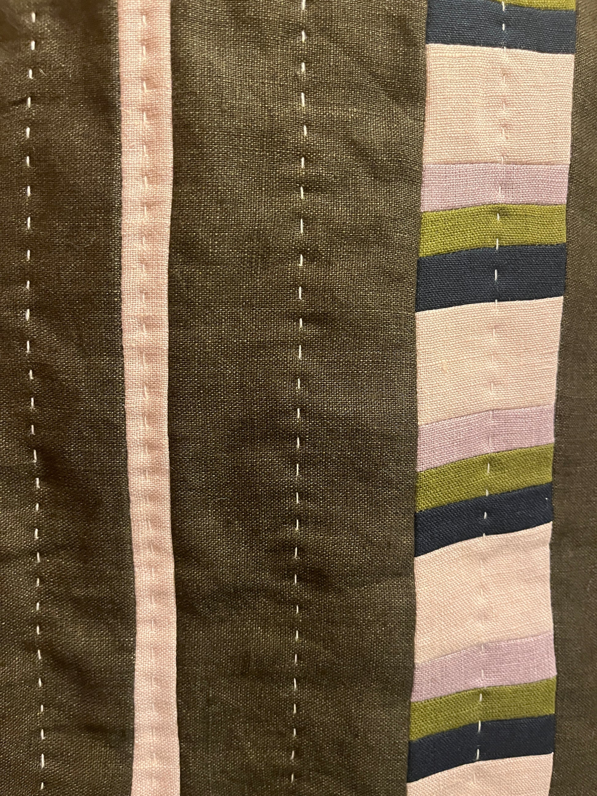 Khaki, mauve, navy and cream quilted wall hanging close up with white stitching