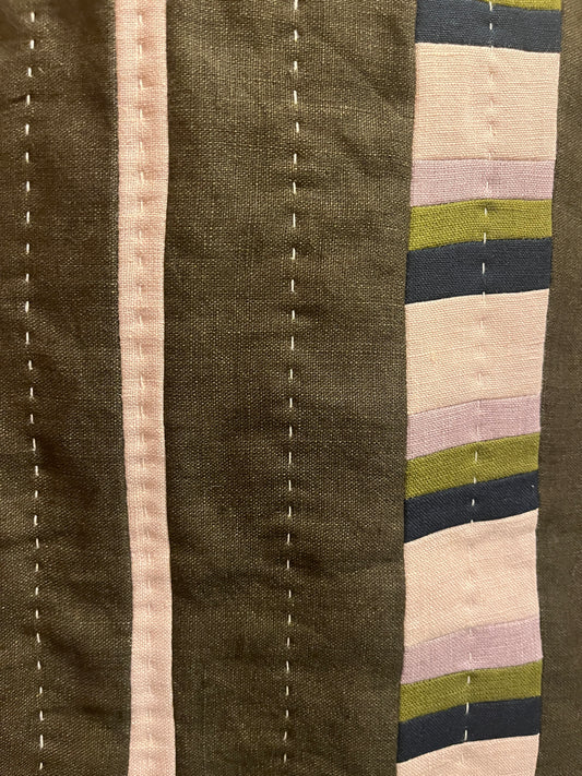 Khaki, mauve, navy and cream quilted wall hanging close up with white stitching