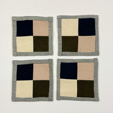 Four checkered coasters with navy, beige, and green squares on a white background