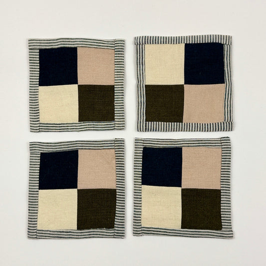 Four checkered coasters with navy, beige, and green squares on a white background