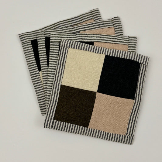 Set of four patchwork linen coasters with checkered pattern on a light gray background