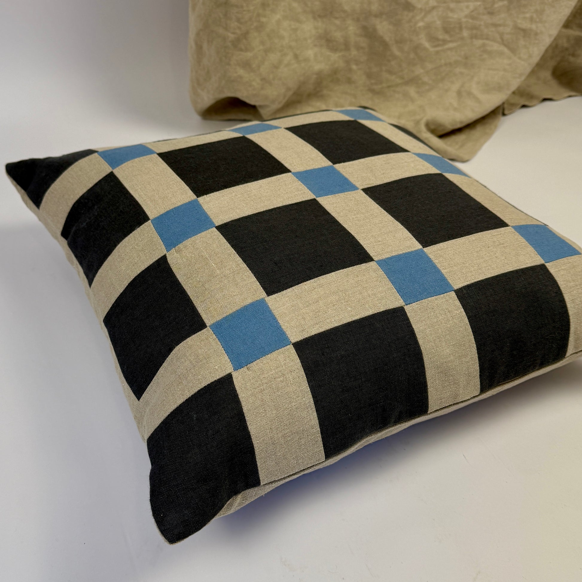 Checkered pillow with navy, blue, and beige pattern on a white background