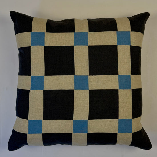 Checkered pillow with navy, beige, and blue pattern on a white background